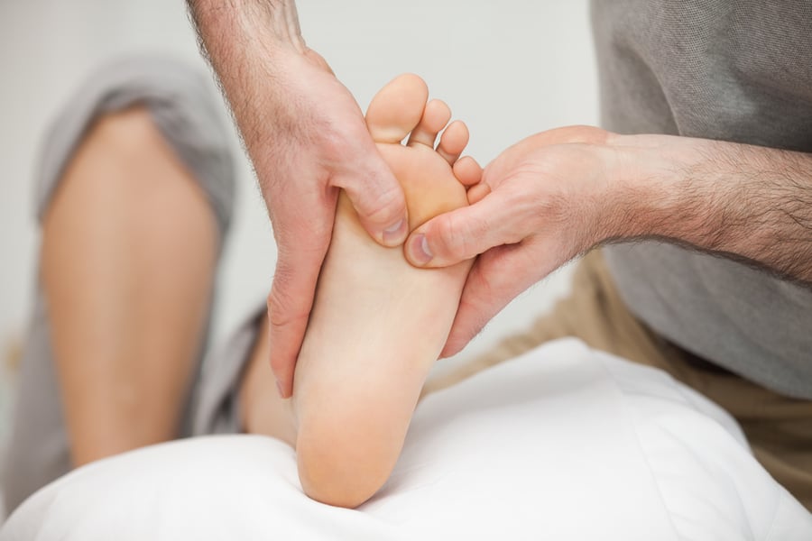 Chiropodist touching the foot of a woman in a medical room