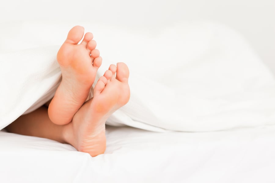 Feet in a bed against a white background