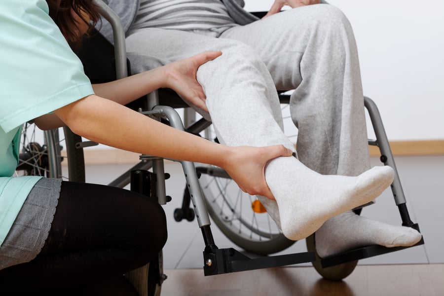 Young physiotherapist exercising with elder disabled person