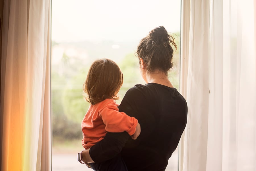 Mom standing holding child looking out window
