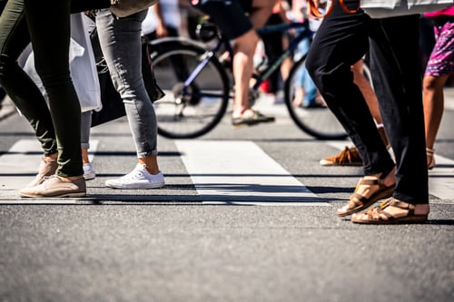 People walking across a busy walkway in city