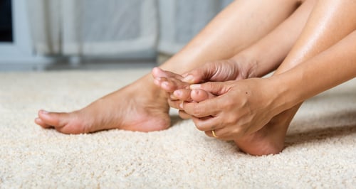 Woman holding foot dealing with foot pain