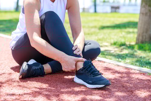 Young woman feeling pain in her ankle