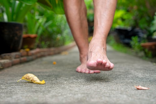Man walking barefoot on cement walkway in the garden