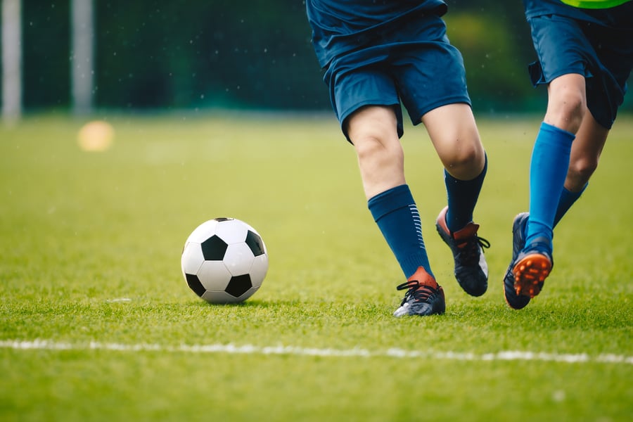 Two soccer players running and kicking a soccer ball