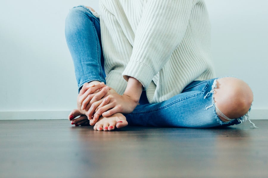 Sweeney Foot & Ankle No Doubt Gout is Painful Young Woman Sitting on Wood Floor Holding Foot in Pain