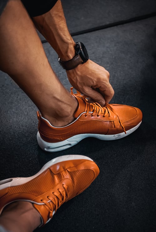 Sweeney Foot and Ankle Athlete's Foot Man Adjusting Laces of Orange Sneakers